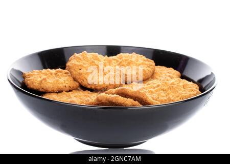 Mehrere süße Torchetti-Kekse mit Haferflocken auf einer schwarzen Keramikplatte, Nahaufnahme, auf weißem Hintergrund. Stockfoto