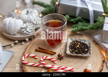 Weihnachten, ein Glas Glühmost oder Wein mit Gewürzen, Zuckerstöcken und Dekorationen. Stockfoto