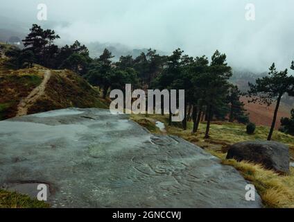 Sehen Sie sich die ungewöhnlichen prähistorischen Felskunstentwürfe nordwestlich am Ausbiss des Hangingstone Quarry Rock oberhalb von Ilkley, West Yorkshire, England, Großbritannien, an. Stockfoto