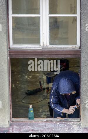 Ein Arbeiter arbeitet an der Rekonstruktion eines Fensters im Haus Stockfoto