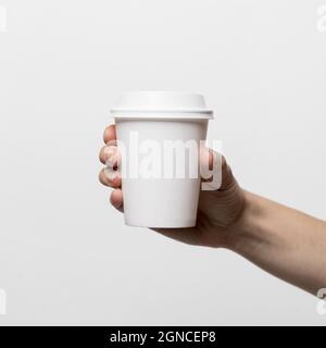 Die Hand hält die weiße Kaffeetasse aus nächster Nähe. Hohe Qualität und Auflösung schönes Fotokonzept Stockfoto