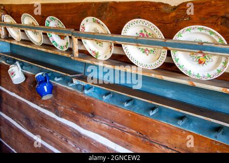 Alte verzierte Teller auf einem Regal in einem Dorfhaus Stockfoto