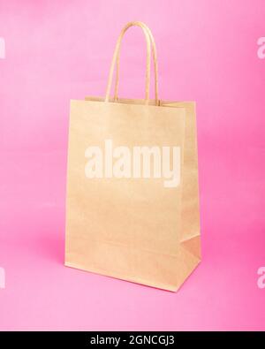 Leere Papiertüte mit Platz für Beschriftungen, Verkaufsmockup auf rosa Hintergrund. Stockfoto