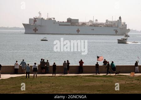 NORFOLK (28. März 2020) Menschen versammeln sich, um zu beobachten, wie das Militärkrankenhaus des Sealift Command USNS Comfort (T-AH 20) die Naval Station Norfolk, VA, verlässt., 28. März 2020. Comfort setzt zur Unterstützung der COVID-19-Reaktionsbemühungen des Landes ein und wird als Überweisungskrankenhaus für Patienten dienen, die nicht COVID-19 sind und derzeit in Küstenkrankenhäusern stationär aufgenommen werden. Dies ermöglicht es den an Land ansässigen Krankenhäusern, ihre Bemühungen auf COVID-19-Fälle zu konzentrieren. Eine der Missionen des Verteidigungsministeriums ist die Unterstützung der Zivilbehörden durch die Verteidigung. Das Verteidigungsministerium unterstützt die Federal Emergency Management Agency, die führende Bundesbehörde, als wel Stockfoto