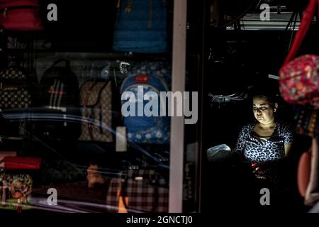 Beirut, Libanon. September 2021. Eine Libanesin sitzt während eines Stromausfalls in einem Kofferladen. Quelle: Marwan Naamani/dpa/Alamy Live News Stockfoto