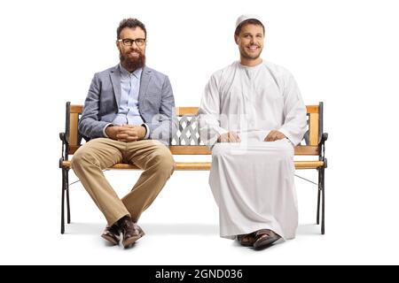 Junger Mann in ethnischer Kleidung und ein zwangloser bärtiger Mann, der auf einer Bank sitzt und isoliert auf weißem Hintergrund lächelt Stockfoto