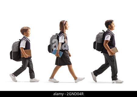 Ganzkörperaufnahme eines Schulmädchen und zweier Schüler, die auf weißem Hintergrund auf einer Linie mit Büchern in ihren Händen gehen Stockfoto