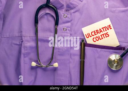 Symbol für Colitis ulcerosa. Medizinische Uniform, weiße Karte mit den Worten Colitis ulcerosa, Metallstift und Stethoskop. Medizinische und ulzerative Colitis conc Stockfoto