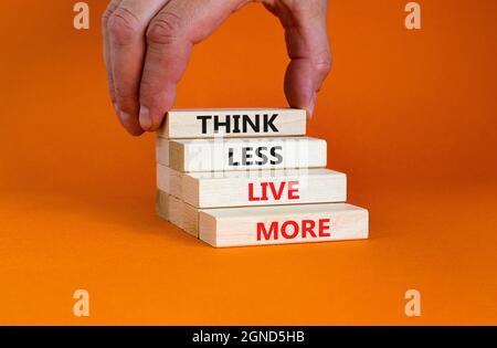 Denken Sie weniger leben mehr Symbol. Blöcke mit Konzeptwörtern denken weniger leben mehr auf einem schönen orangen Hintergrund. Geschäftsmann Hand. Business, psychologica Stockfoto