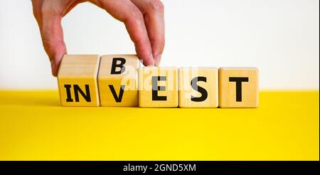 Symbol für beste Investition. Geschäftsmann dreht Holzwürfel und ändert das Wort „investieren“ in „am besten“. Schöner weißer Hintergrund. Geschäft und beste Investitionen conce Stockfoto