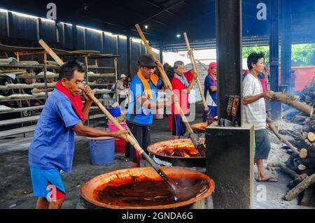 Die Arbeiter der traditionellen Kuchenfabrik, nämlich Keranjang- und Dodol-Kuchen, kneten den Teig, der auf einem Holzofen gekocht wird. Stockfoto