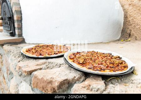 Pizza aus einem weiß lackierten, handgefertigten Holzofen, der auf der Außenseite gebaut wurde Stockfoto