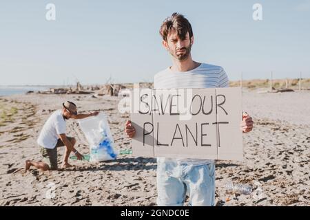 Eine Gruppe aktivistischer Freunde sammelt Plastikmüll am Strand. Leute putzen den Strand, mit Taschen. Konzept des Umweltschutzes und des Ozeans Stockfoto
