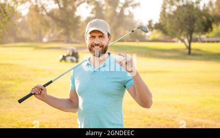 Fröhlicher männlicher Golfspieler auf einem Profikurs mit grünem Gras halten Ball, Sport Stockfoto