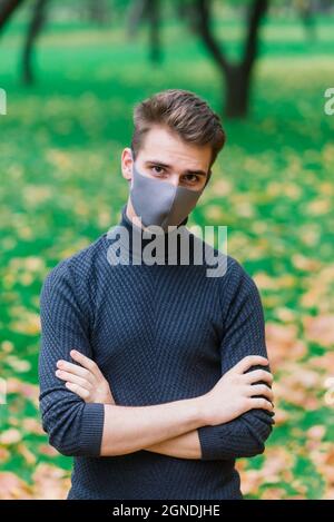 Junger Mann in einer Grippemaske im Herbstpark Stockfoto