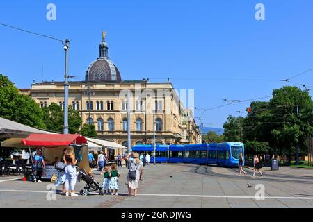 Eine blaue Straßenbahn, die am Starcevicev Dom (ehemalige Residenz der kroatischen Politikerin und Schriftstellerin Ante Starcevic (1823-1896) in Zagreb, Kroatien, vorbeifährt Stockfoto