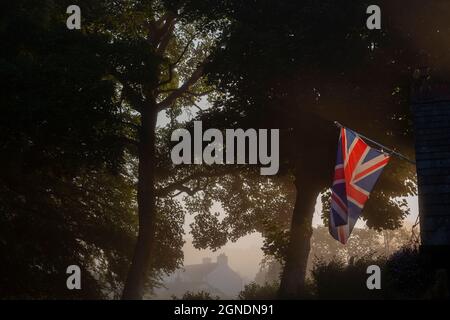 Union Jack im Nebel.die Flagge des Vereinigten Königreichs an einem schönen nebligen Morgen bei Sonnenaufgang. Stockfoto