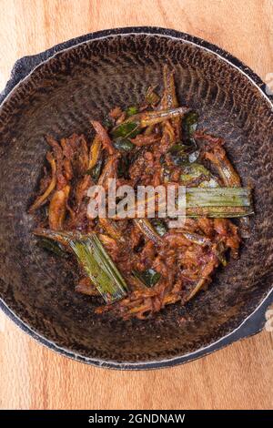 Gebratenes kleines trockenes Fischgericht, gekochte Meeresfrüchte mit Kokosöl und Gewürzen in einer Pfanne umrühren, Nahaufnahme Stockfoto