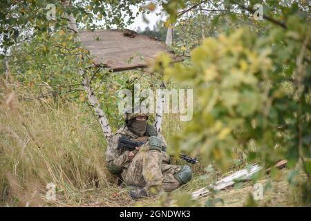 Lviv, Ukraine. September 2021. Ein ukrainisches Militär, das während der internationalen Militärübungen 'Rapid Trident - 2021' im Gras verkleidet gesehen wurde.auf dem Territorium des Internationalen Zentrums für Friedenssicherung und Sicherheit der Nationalen Akademie der Landstreitkräfte, benannt nach Hetman Petro Sahaidachny, Ukrainisch-amerikanische Kommando- und Stabsübungen mit Truppen "Rapid Trident - 2021" finden statt, die am 20. September begonnen haben und bis zum 1. Oktober 2021 dauern werden. An den Übungen nehmen Soldaten aus 15 Ländern Teil (Ukraine, USA, Deutschland, Bulgarien, Georgien, Italien, Polen, Rumänien, Großbritannien und andere Stockfoto