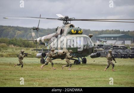 Lviv, Ukraine. September 2021. Soldaten laufen in der Nähe des Hubschraubers nach der Landung während der internationalen Militärübung „Rapid Trident – 2021“ auf dem Gebiet des Internationalen Zentrums für Friedenssicherung und Sicherheit der Nationalen Akademie der Landstreitkräfte, benannt nach Hetman Petro Sahaidachny, Ukrainisch-amerikanische Kommando- und Stabsübungen mit Truppen "Rapid Trident - 2021" finden statt, die am 20. September begonnen haben und bis zum 1. Oktober 2021 dauern werden. An den Übungen nehmen Soldaten aus 15 Ländern Teil (Ukraine, USA, Deutschland, Bulgarien, Georgien, Italien, Polen, Rumänien, Großbritannien und Stockfoto