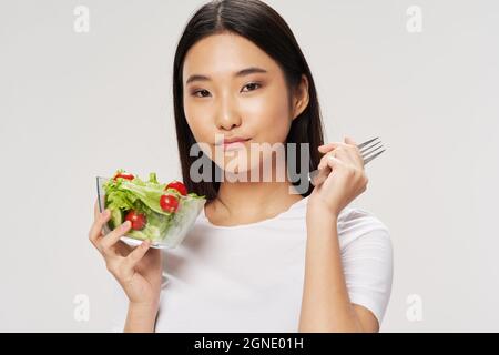 Frau Salate Teller asiatisch sieht T-Shirt hellen Hintergrund Stockfoto