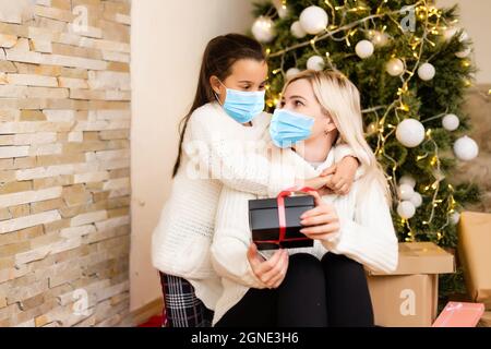 Menschen mit Geschenken tragen Gesichtsmasken während Coronavirus und Grippe Ausbruch an Weihnachten. Schutz vor Viren und Krankheiten, Quarantäne zu Hause. COVID-2019 Stockfoto