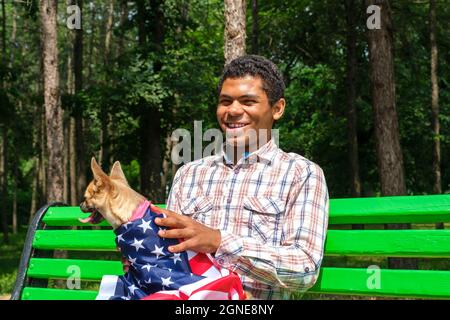 Lächelnder afroamerikanischer Mann mit Hund entspannt auf der Bank Stockfoto