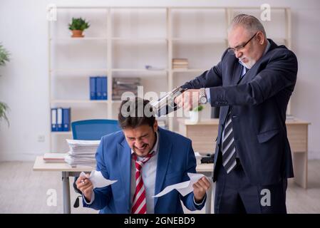 Alter Chef und junger Mitarbeiter im Mobbing-Konzept Stockfoto