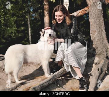 Vorderansicht der jungen lächelnden Frau streichelte ihren Hund whlen unter dem Baum in einem Wald sitzen. Wandern mit Hund, Haustier Freund Stockfoto