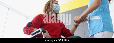 Arzt Physiotherapeut in schützende medizinische Maske arbeitet aus der Hand des behinderten Patienten in der Klinik Stockfoto