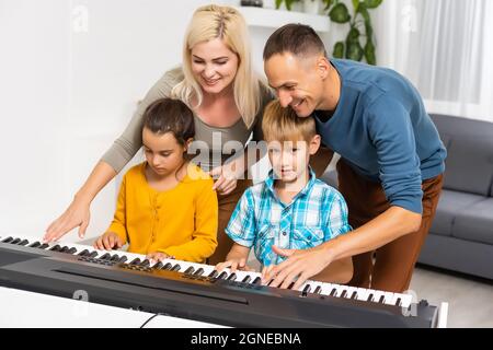 Kaukasische Familie spielt gemeinsam Musikinstrumente, Kinder spielen Synthesizer im Wohnzimmer Stockfoto