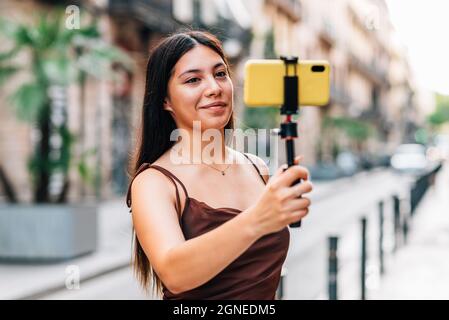 Attraktive junge asiatische Frau vloggt mit ihrem Smartphone in den Straßen von Barcelona Stockfoto
