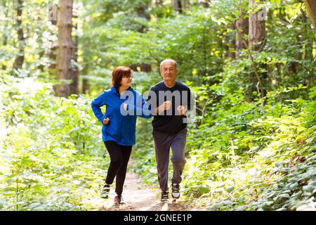 Glückliches Seniorenpaar, das im Park zusammenläuft Stockfoto