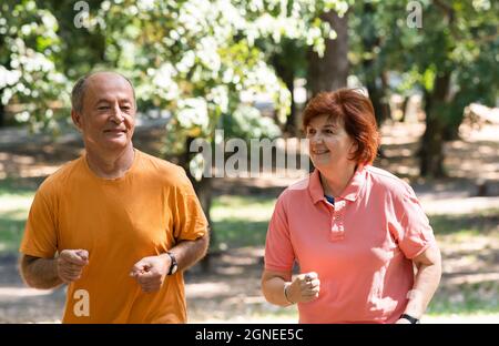 Glückliches Seniorenpaar, das im Park zusammenläuft Stockfoto