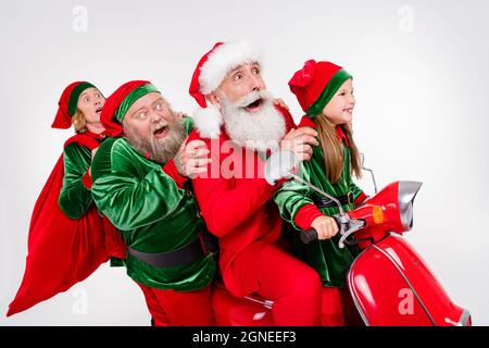 Foto von verrückten Team vier Menschen fahren Roller Eile Party tragen santa Elf Kostüm isoliert grauen Hintergrund Stockfoto