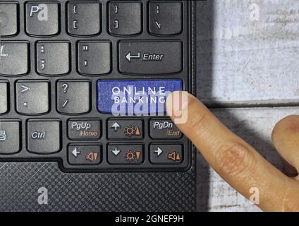 Fingerdruck auf eine blaue Taste mit der Bezeichnung ONLINE-BANKING mit Symbol auf einem Computertastaturkonzept Stockfoto