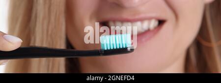Lächelnde Frau mit Zahnbürste vor ihrer Nahaufnahme Stockfoto