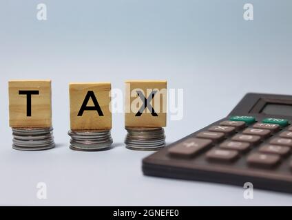 Taschenrechner und STEUERWORT auf Holzblock geschrieben. Stockfoto