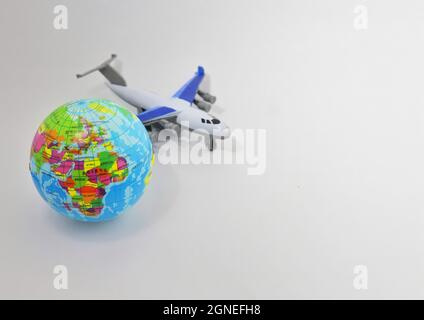 Spielzeugflugzeug und Erdkugel auf weißem Hintergrund mit Kopierraum. Selektiver Fokus. Stockfoto