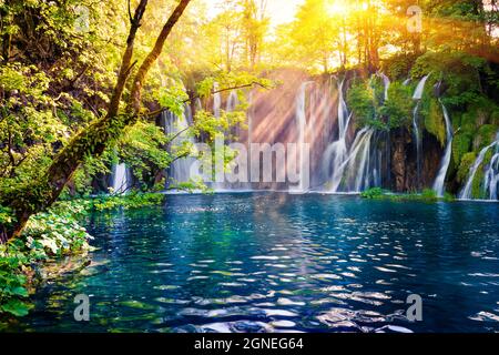 Letztes Sonnenlicht erhellt den reinen Wasserfall im Plitvice National Park. Bunte Frühlingsszene von grünem Wald mit blauem See. Tolle Landschaft vi Stockfoto