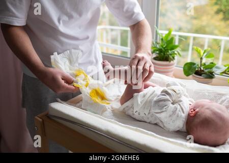 Kaukasischer Vater, der sich um seine neugeborene Tochter oder seinen Sohn kümmert, der die Windel wechselt Stockfoto