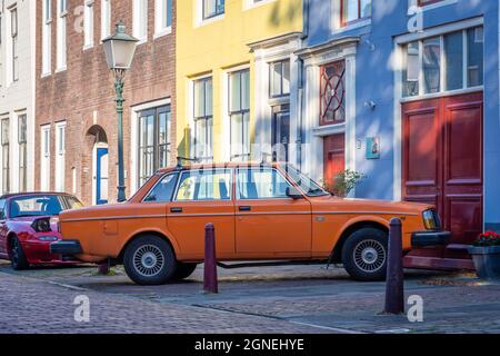 Klassisches Volvo-Auto, Modell 244DL in orangefarbener Farbe, geparkt in der farbenfrohen holländischen Straße Stockfoto