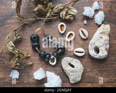 Geheime oder geheimnisvolle Inhaltsstoffe: talisman, trockene Kräuter, Kaurimuscheln, Kristalle und seltene Steine mit Löchern. Geist- oder heidnische Rituale Stockfoto