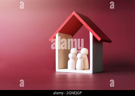 Familienpflege, Schutz und Versicherungskonzept. Hölzerne Puppenfamilie in einem Haus. Stockfoto