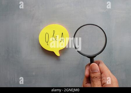 Frage- und Antwortkonzept. Lupe und Sprechblase mit den Texten Q und A in der Hand halten Stockfoto