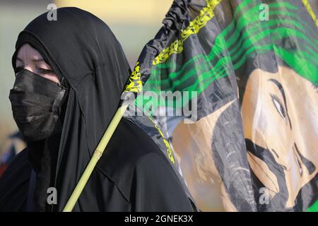 Bagdad, Irak. September 2021. Eine Frau, die eine Flagge trägt, marschiert mit schiitischen Muslimen aus Bagdad, um die Husain-Moschee in Karbala anlässlich des Arba'een zu besuchen, der auch als Chehelom bekannt ist, eine religiöse Feier, die vierzig Tage nach dem Tag der Aschura stattfindet, um des Martyriums von Husain ibn Ali zu gedenken, Der Enkel des islamischen Propheten Muhammad, der nach islamischem Kalender am 10. Tag des Monats Muharram getötet wurde. Quelle: Ameer Al Mohammedaw/dpa/Alamy Live News Stockfoto