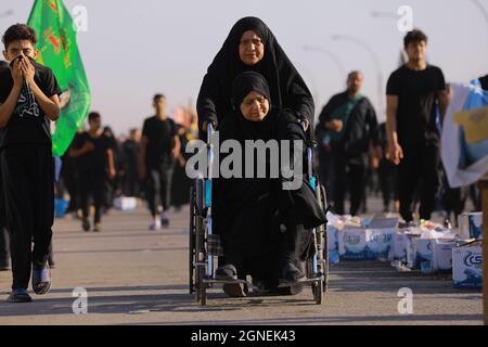 Bagdad, Irak. September 2021. Zwei Frauen marschieren mit schiitischen Muslimen aus Bagdad, um die Husain-Moschee in Karbala anlässlich des Arba'een zu besuchen, der auch als Chehelom bekannt ist, eine religiöse Begebenheit, die vierzig Tage nach dem Tag der Aschura stattfindet, um des Martyriums von Husain ibn Ali zu gedenken, Der Enkel des islamischen Propheten Muhammad, der nach islamischem Kalender am 10. Tag des Monats Muharram getötet wurde. Quelle: Ameer Al Mohammedaw/dpa/Alamy Live News Stockfoto