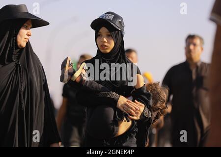 Bagdad, Irak. September 2021. Eine irakische Familie marschiert mit schiitischen Muslimen aus Bagdad, um die Husain-Moschee in Karbala anlässlich des Arba'een zu besuchen, der auch als Chehelom bekannt ist, eine religiöse Begebenheit, die vierzig Tage nach dem Tag der Aschura stattfindet, um des Martyriums von Husain ibn Ali zu gedenken, Der Enkel des islamischen Propheten Muhammad, der nach islamischem Kalender am 10. Tag des Monats Muharram getötet wurde. Quelle: Ameer Al Mohammedaw/dpa/Alamy Live News Stockfoto