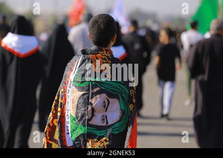 Bagdad, Irak. September 2021. Ein junger Mann, der eine Flagge trägt, marschiert mit schiitischen Muslimen aus Bagdad, um die Husain-Moschee in Karbala anlässlich des Arba'een zu besuchen, der auch als Chehelom bekannt ist, eine religiöse Begebenheit, die vierzig Tage nach dem Tag der Aschura stattfindet, um des Martyriums von Husain ibn Ali zu gedenken, Der Enkel des islamischen Propheten Muhammad, der nach islamischem Kalender am 10. Tag des Monats Muharram getötet wurde. Quelle: Ameer Al Mohammedaw/dpa/Alamy Live News Stockfoto