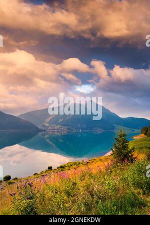 Unglaublicher Sommersonnenaufgang am Reschensee. Große Morgenansicht von Graun Vinschgau Dorf, Alpen, Italien, Europa. Schönheit der Natur Konzept bac Stockfoto